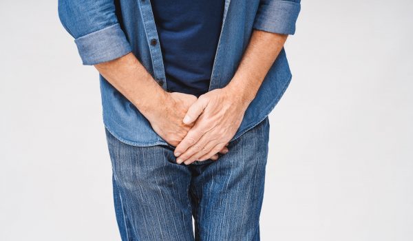 Cropped portrait of senior man suffering from prostatitis or venereal disease, posing in studio, isolated on white. Urological diseases, pain during urination concept