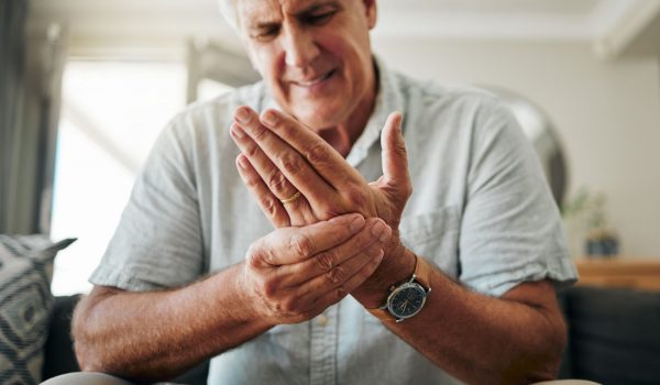 Hands, pain and arthritis with a senior man holding his hand while suffering from osteoporosis, cra.